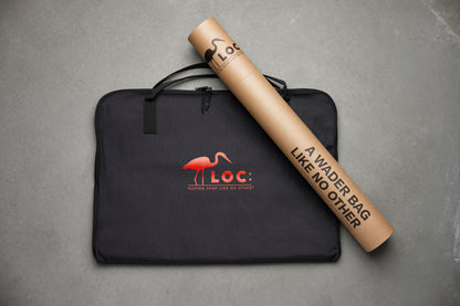 A black zippered carrying bag with a red LOC logo and a rolled tan paper tube printed with the same brand name and slogan, placed on a gray textured surface.